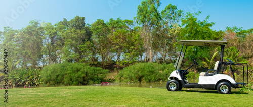 Golf cart car in fairway of golf course with fresh green grass field and cloud sky and tree,panorama