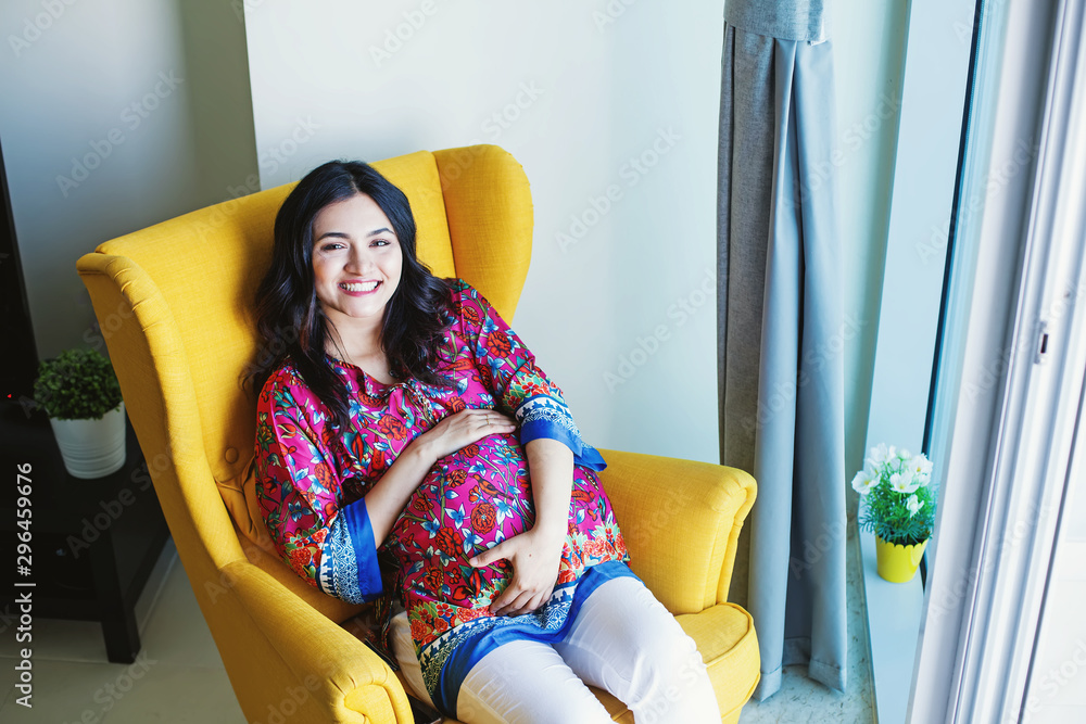 Φωτογραφία Young pregnant Indian woman sitting in armchair at home