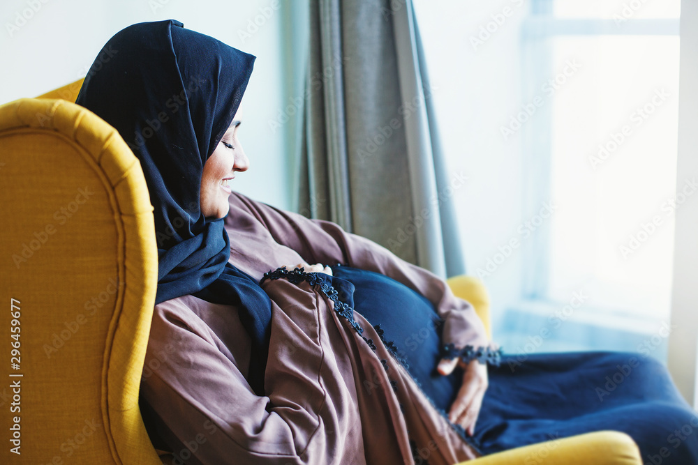 Εκτύπωση καμβά Young pregnant Indian woman sitting in armchair at home