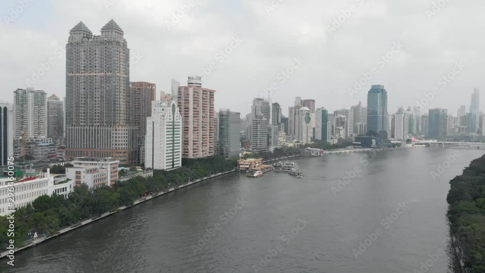 A drone flies over the river, on two sides are tall buildings, in the center of attention is the ferry station, to which the boat is moored A drone flies over the river, on two sides are tall buildings, in the center of attention is the ferry station, to which the boat is moored