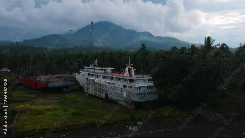 Aerial drone view of an abandoned cruise shipwreck on an isolated tropical island with a dormant volcano in the foreground Aerial drone view of an abandoned cruise shipwreck on an isolated tropical island with a dormant volcano in the foreground