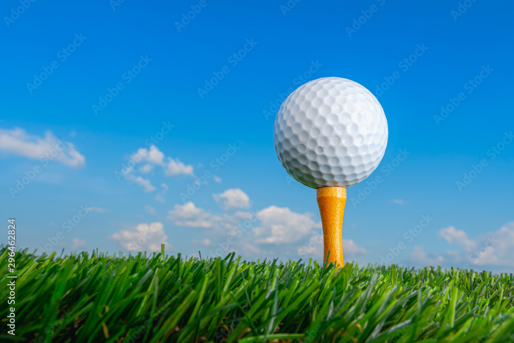 golf ball on tee pegs ready to play in the green grass and blue sky