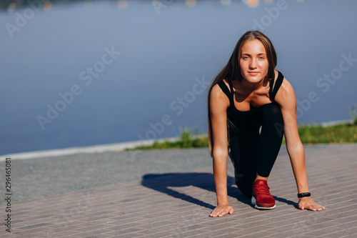 Sporty girl warmimg up outdoor and stretching her legs looking at the camera- Image photo