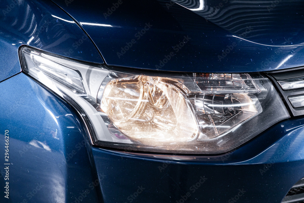 Macro view of modern car xenon lamp headlight, bumper, wheel. Exterior of a modern car.