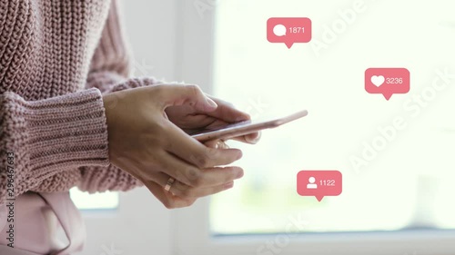 Woman blogger browsing phone, indicators with sign of likes, comments and followers over it, hands closeup. Rising datas of counters. Concept of working in social network and popularity.