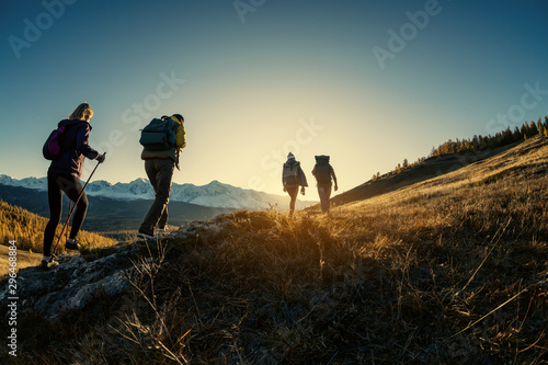 Fényképezés Group of hikers walks in mountains at sunset