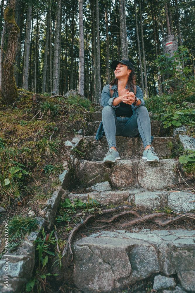 Fototapeta premium smiling woman hiker sitting at stone stairs