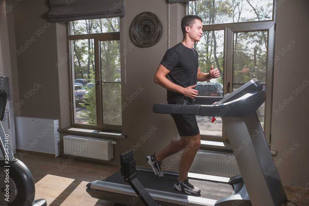 Athlete engaged in the gym, a Young man doing cardio on the treadmill