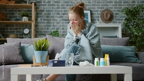 Young woman covered with blanket is coughing in paper tissue wiping nose feeling sick at home. Human health problems, treatment and lifestyle concept. photo