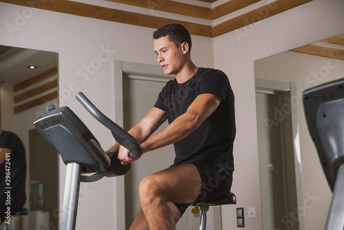 An athlete is engaged in the gym, a Young man does cardio on an exercise bike