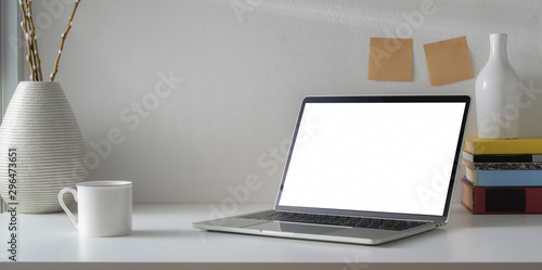 Minimal workspace with open blank screen laptop computer and coffee cup