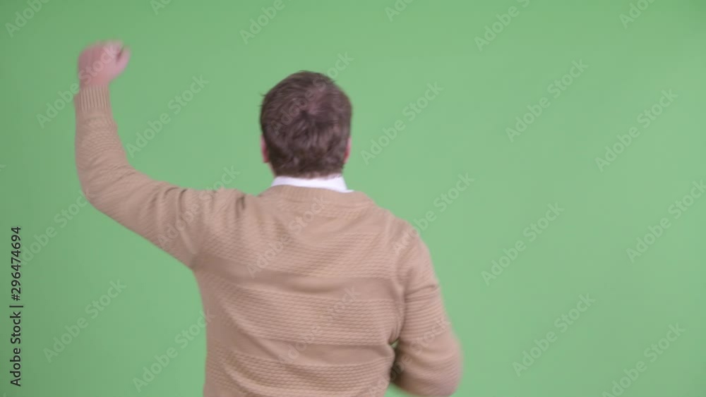 Rear view of happy overweight bearded man with fists raised Rear view of happy overweight bearded man with fists raised
