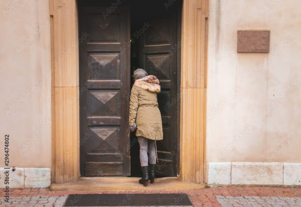 Una joven cotilla dentro de un edificio. Imagen de invierno con abrigo y sombrero dando la espalda al fotógrafo.