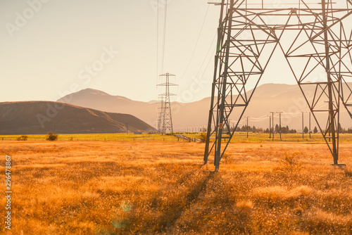 High voltage electrical pole in wide meadows at country side of South Island New Zealand with warm color tone of sunny day. Scenic view of sight seeing while driving around South Island street.