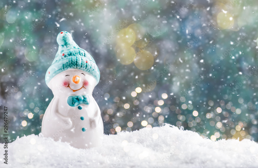 Porcelain snowman figurine in snowdrift, Christmas or New Year background with snowflakes and lights