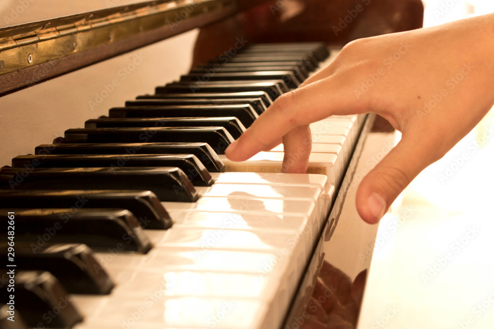 The girl's hand on the piano keys. Piano keys background. Selective focus.