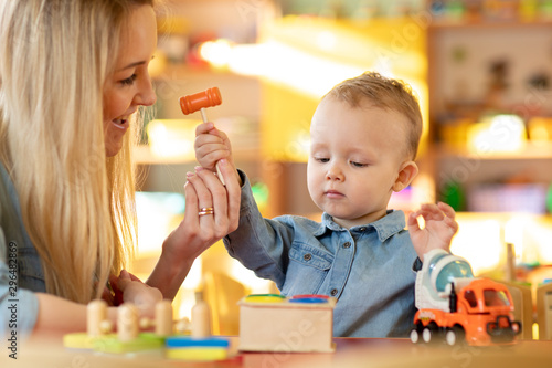 Valokuva kid and mother or baby sitter playing together with toy