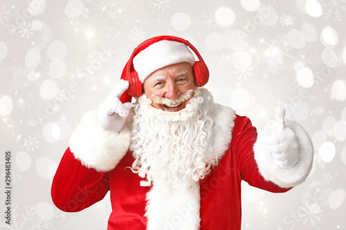 Portrait of Santa Claus listening to music on light background © Pixel-Shot