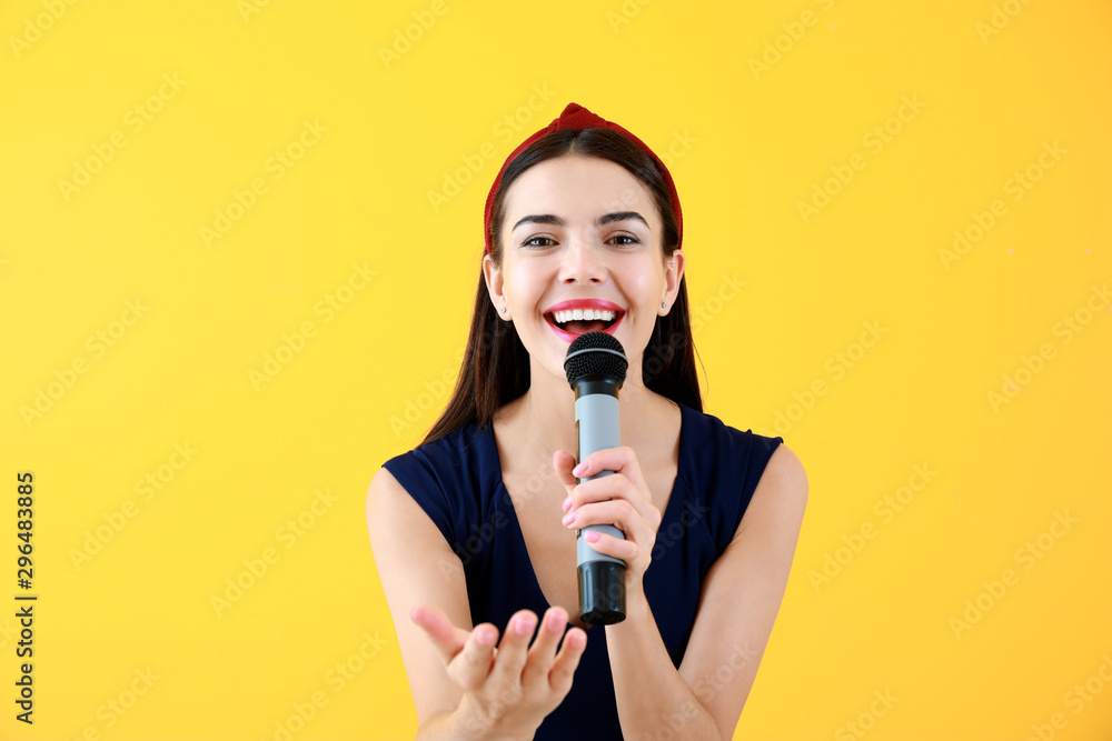 Beautiful young female singer with microphone on color background Beautiful young female singer with microphone on color background