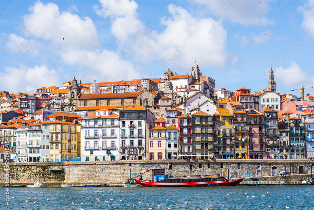 The skyline of Porto in Portugal with a red boat on the river