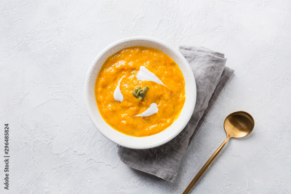 Pumpkin soup with cream on grey stone background. Copy space. Top view.