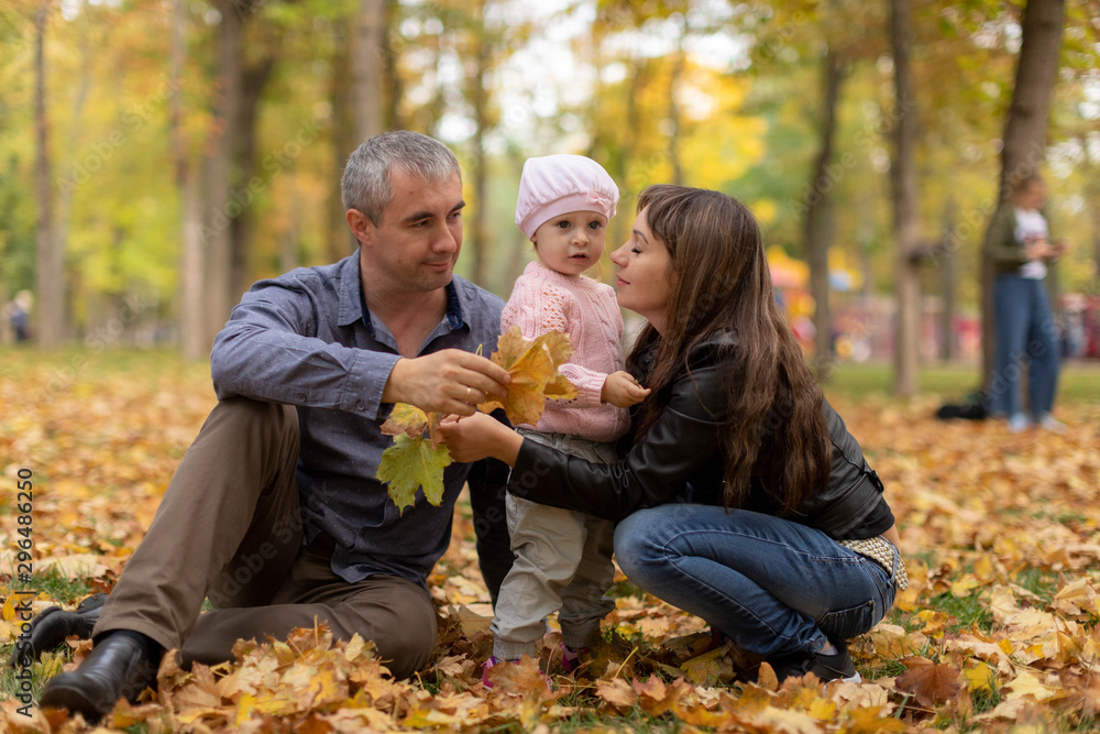 Happy family together in autumn garden/park. Parents with their children are sitting on coverlet in park. Outdoor in full height photo. Family concept Happy family together in autumn garden/park. Parents with their children are sitting on coverlet in park. Outdoor in full height photo. Family concept