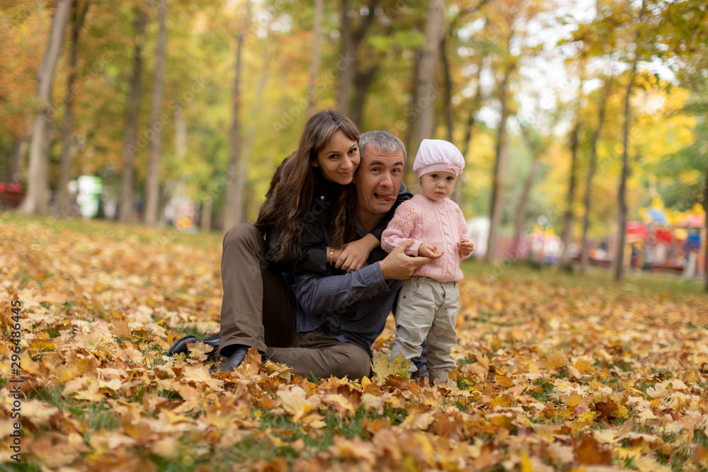 Happy family together in autumn garden/park. Parents with their children are sitting on coverlet in park. Outdoor in full height photo. Family concept Happy family together in autumn garden/park. Parents with their children are sitting on coverlet in park. Outdoor in full height photo. Family concept