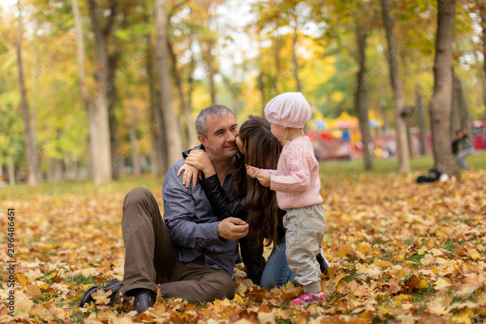 Happy family together in autumn garden/park. Parents with their children are sitting on coverlet in park. Outdoor in full height photo. Family concept Happy family together in autumn garden/park. Parents with their children are sitting on coverlet in park. Outdoor in full height photo. Family concept
