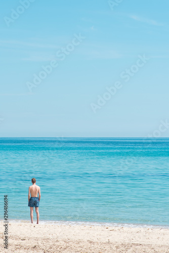 un homme sur la plage regardant la mer en été pendant les vacances