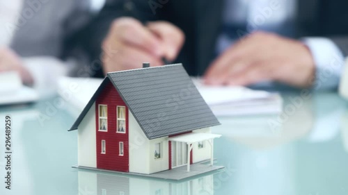 Businessman signs contract behind home architectural model