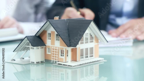 Businessman signs contract behind home architectural model