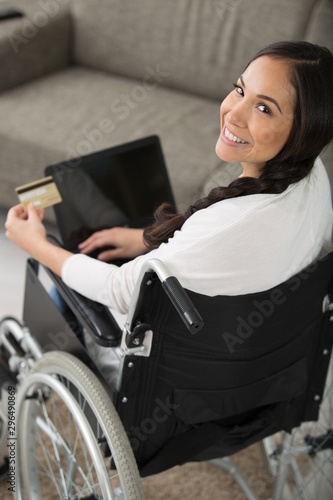 woman in wheelchair making an online purchase on her laptop