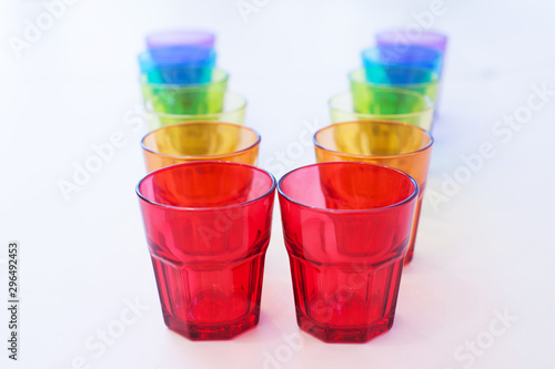 multi-colored glass on a white background. containers made of glass, ordered by the rainbow color spectrum, isolated, purple, blue, green, yellow, orange, red, with clipping path.