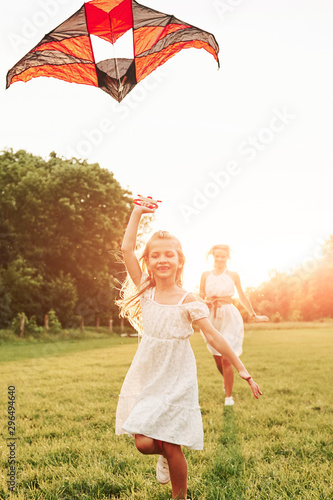 Straight forward. Mother and daughter have fun with kite in the field. Beautiful nature