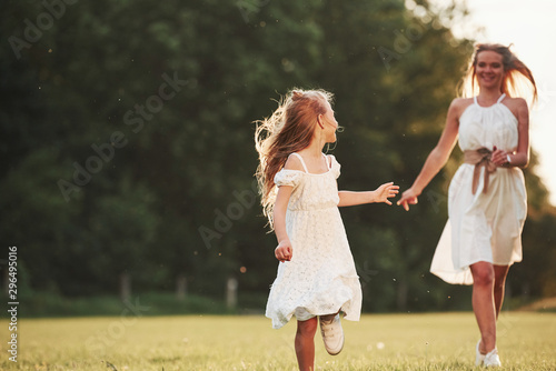 Hey, come with me. Mother and daughter enjoying weekend together by walking outdoors in the field. Beautiful nature