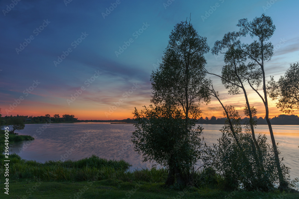 Landscape evening with sunset on a lake with lilies, with beautiful sky in summer season