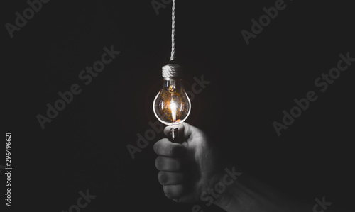 New idea concept. Man is holding lightener near the lamp bulb. Black and white photo. photo