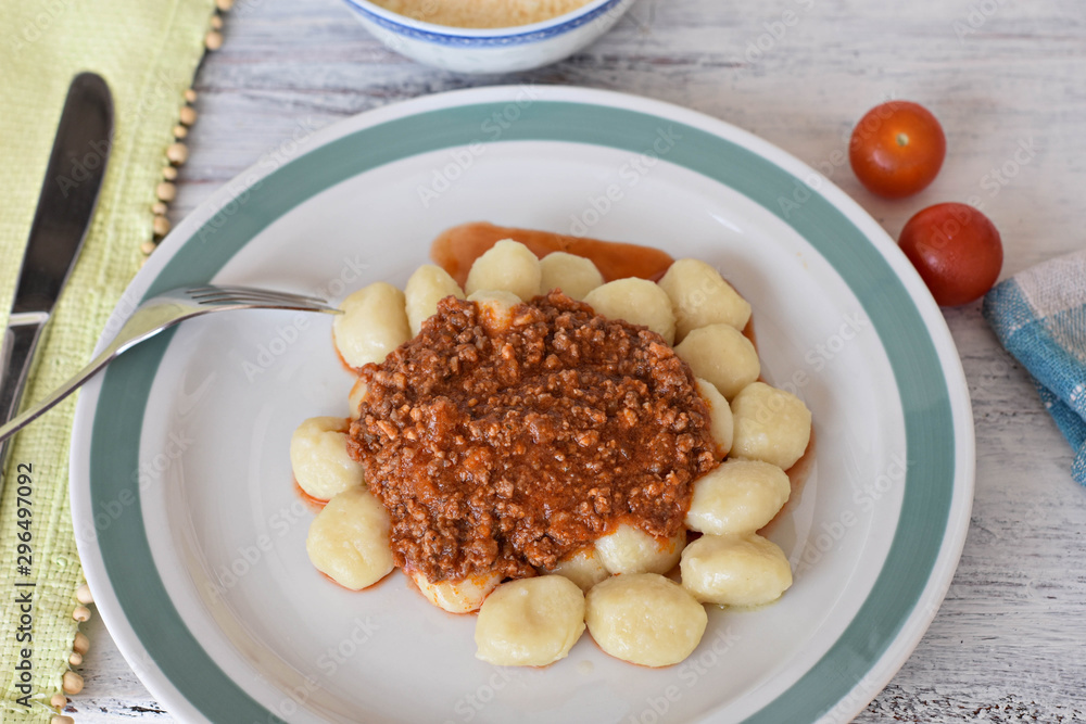 Potato gnocchi, Italian potato dumplings whit red meat sauce, cherry tomatoes at light wooden background