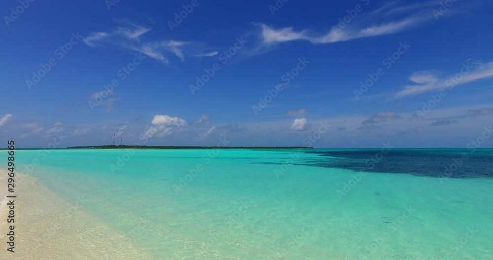 Vivid clear teal water flows across the frame onto a clean tan beach in the Caribbean Vivid clear teal water flows across the frame onto a clean tan beach in the Caribbean