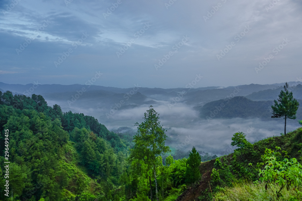 Beautiful landscape with green mountains and magnificent cloudy sky in sunrise. Buluh Payung Hill, Kebumen, Central Java, Indonesia