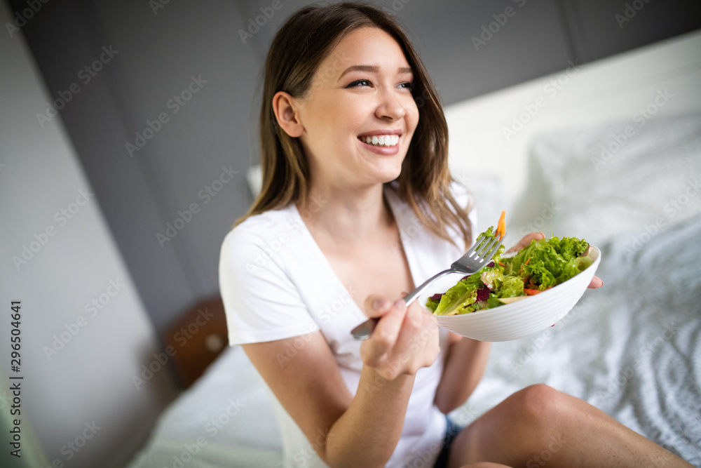 Young woman eating healthy salad after working out at home Young woman eating healthy salad after working out at home