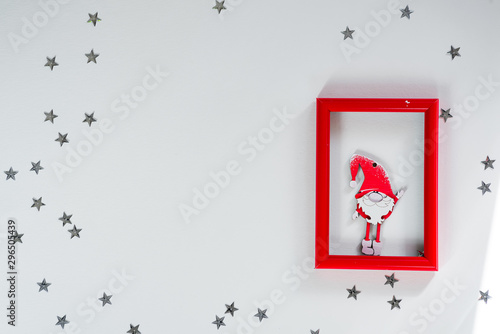 Funny handmade red gnom on frame with silver stars on white christmas background for a greeting card. Copy space flat lay