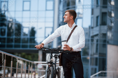 Ready for the work. Businessman in formal clothes with black bicycle is in the city