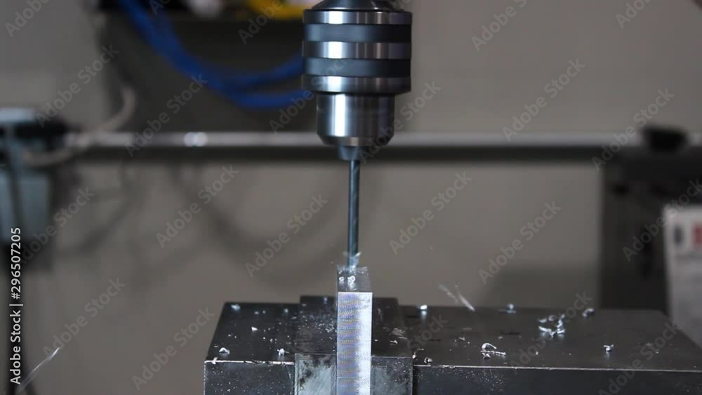 Drill press lowered and peck drilled into piece of aluminum straight on view Drill press lowered and peck drilled into piece of aluminum straight on view