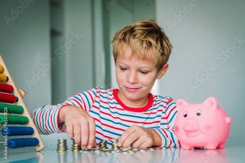 Fotografi child counting money, boy put coins into piggy bank
