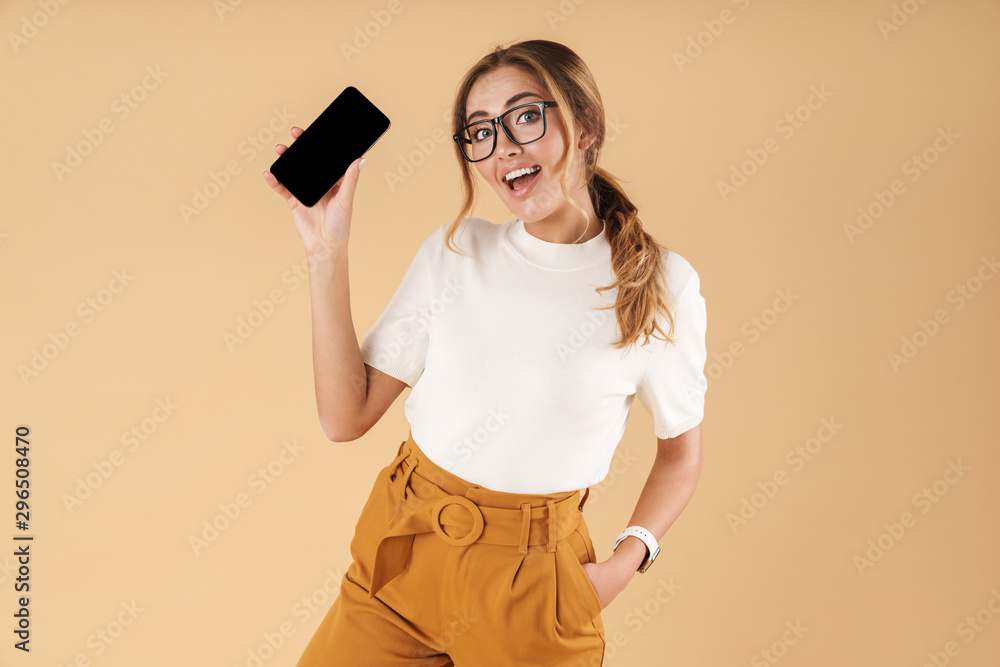Image of optimistic young woman smiling and holding smartphone Image of optimistic young woman smiling and holding smartphone