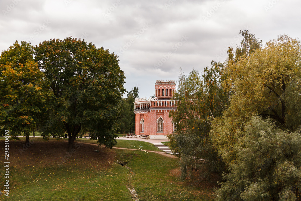 The tower of a beautiful old castle surrounded by autumn trees against a gray sky. The tower of a beautiful old castle surrounded by autumn trees against a gray sky.