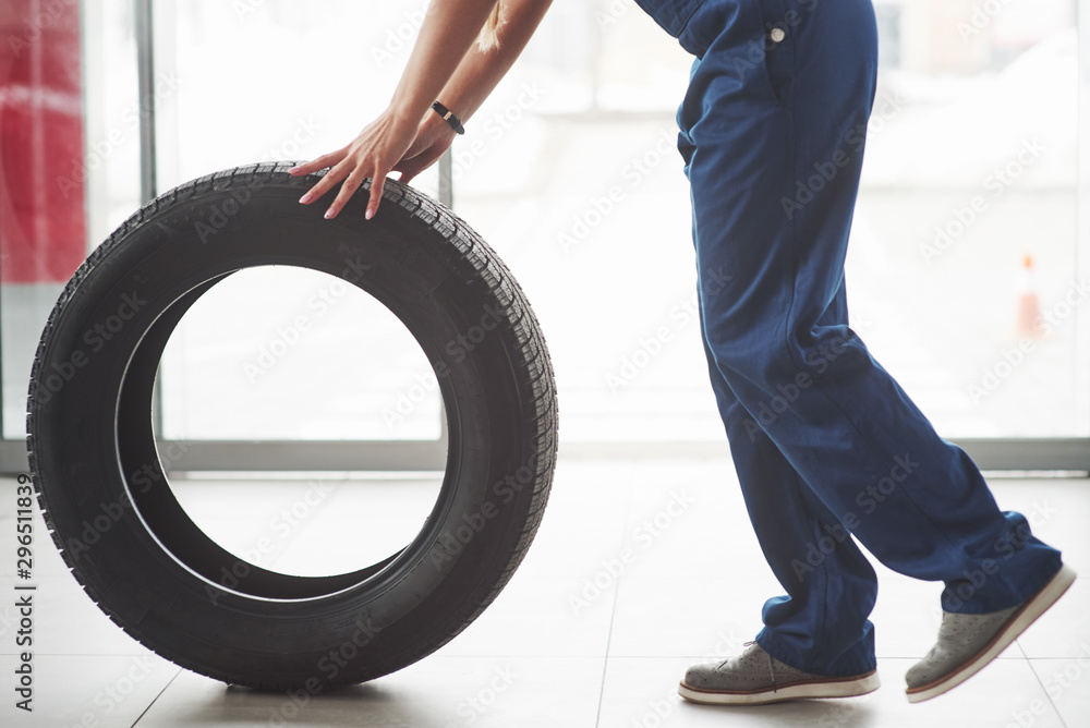 Cropped photo. Woman walks with brand new wheel to the car. Conception of repair Cropped photo. Woman walks with brand new wheel to the car. Conception of repair