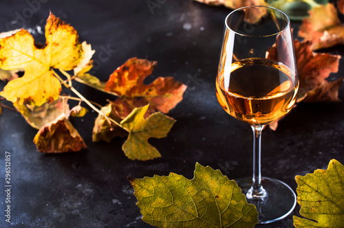 Glass of white wine and wine bottle in close up view of the wineglasses over abstract gray background with copy space photo