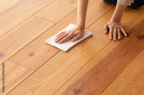木目の床を雑巾で拭く若い女性の手元
